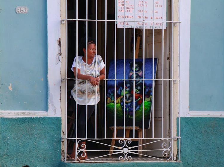 Woman Standing Near Painting Behind Bars