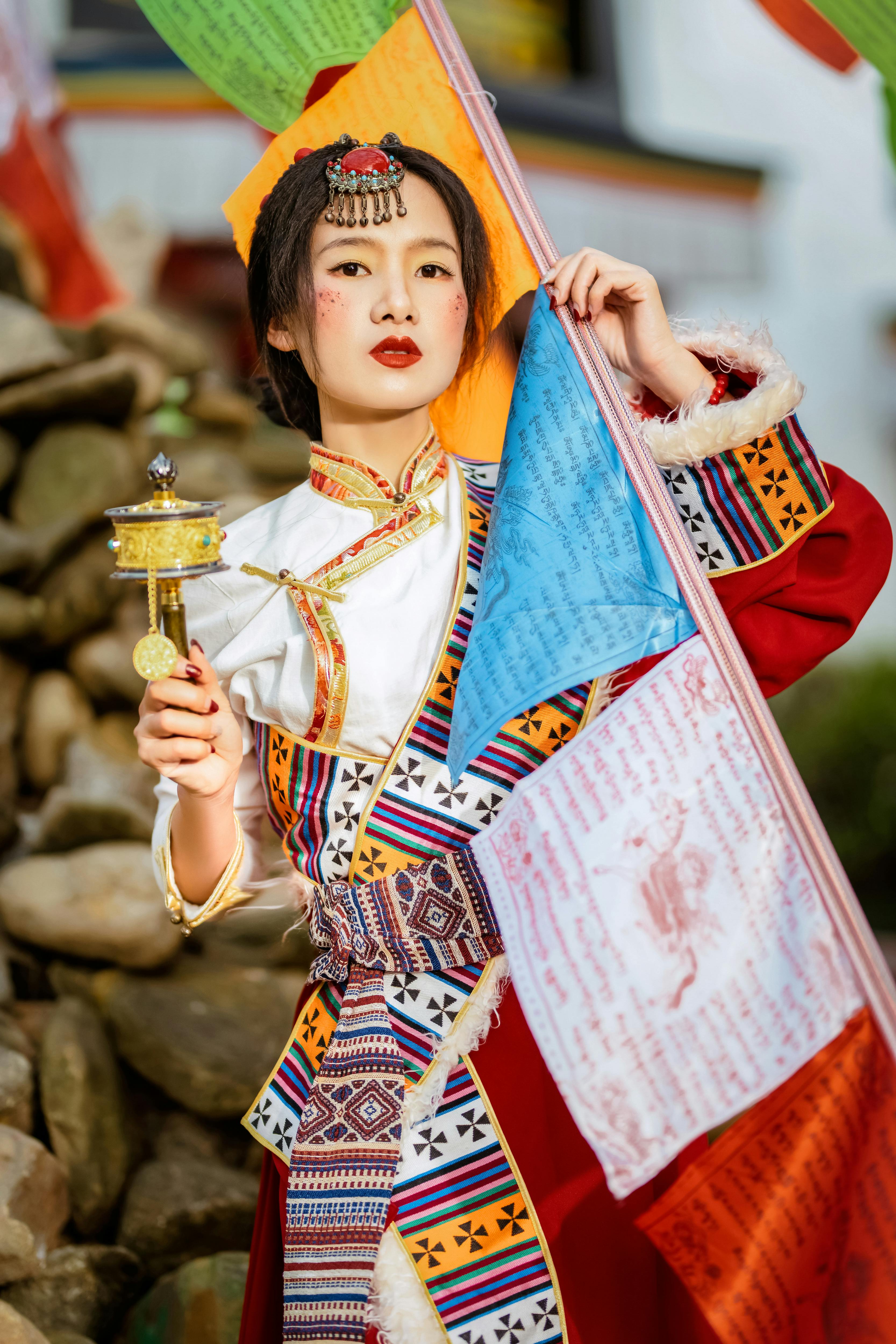Woman in vibrant traditional attire holding prayer flags, representing cultural richness in Shenzhen.
