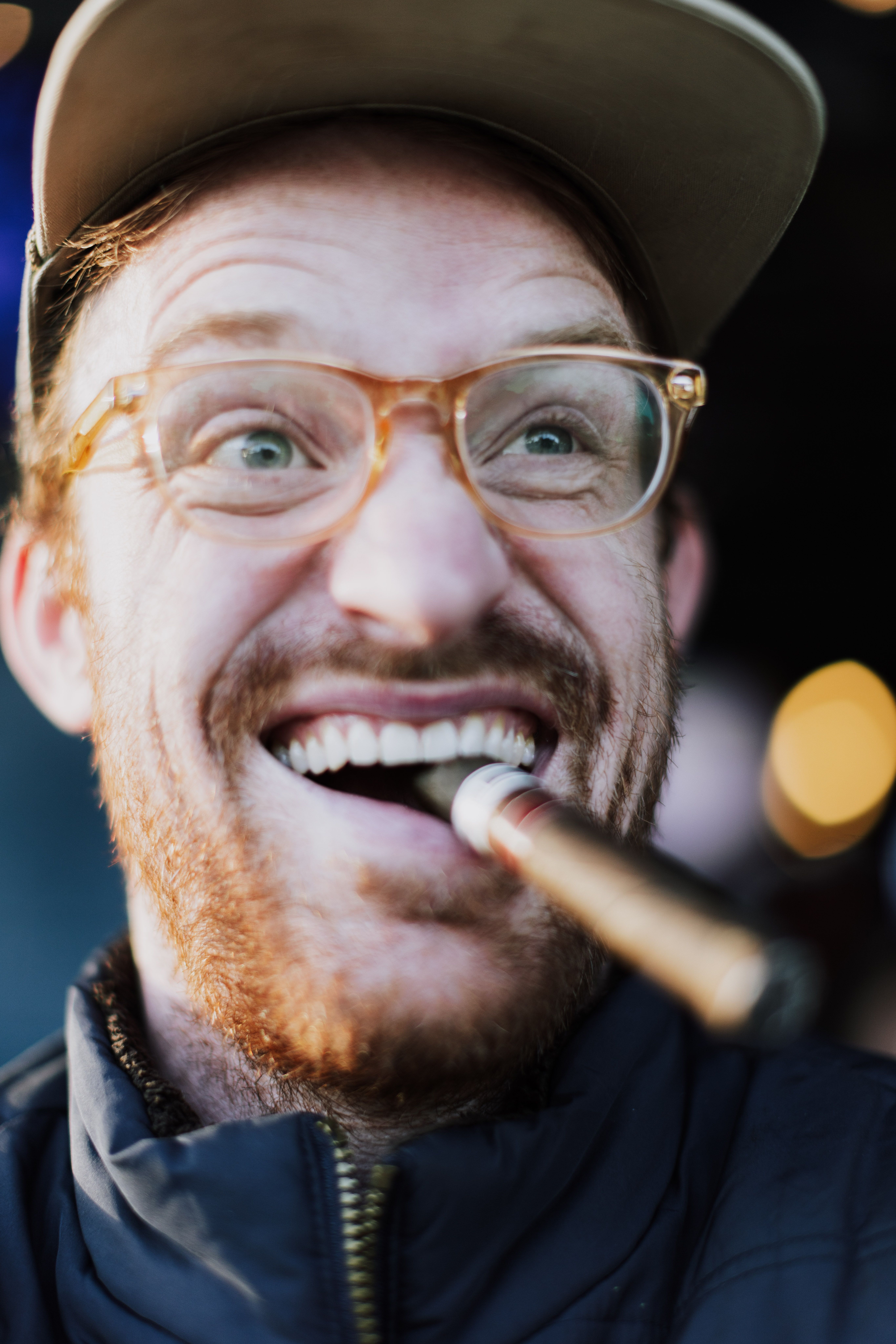 Cheerful man in glasses, cap, and cigar enjoying outdoor atmosphere.