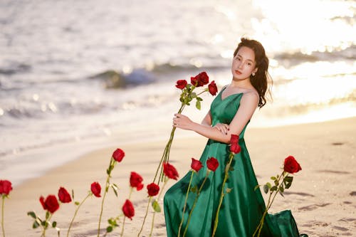 Model in Satin Dress with Red Roses at Beach