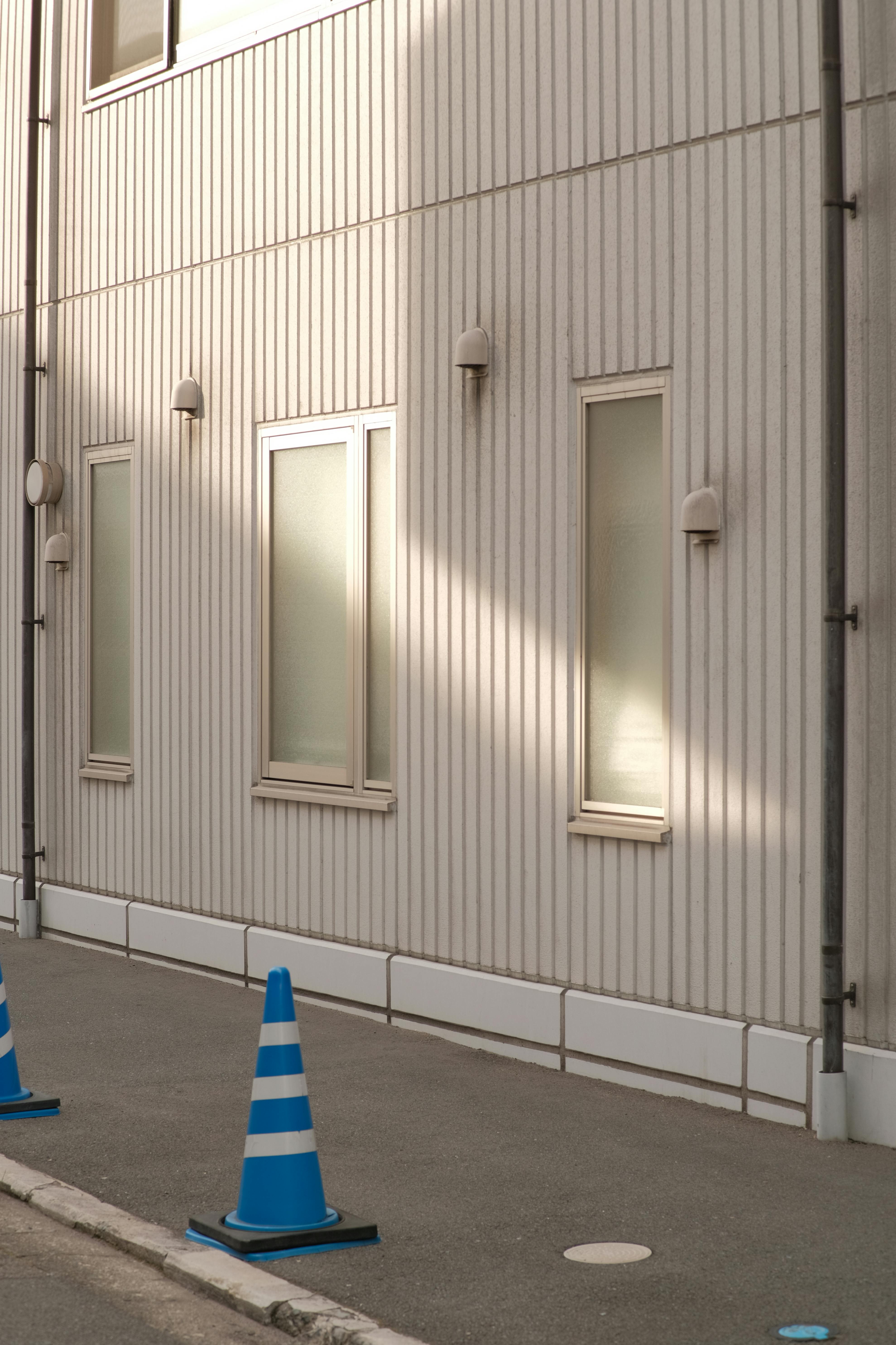 Exterior view of building facade with blue traffic cone on sidewalk.
