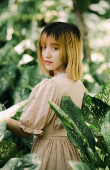 A serene image of a woman standing amidst lush greenery, exuding tranquility and natural beauty.