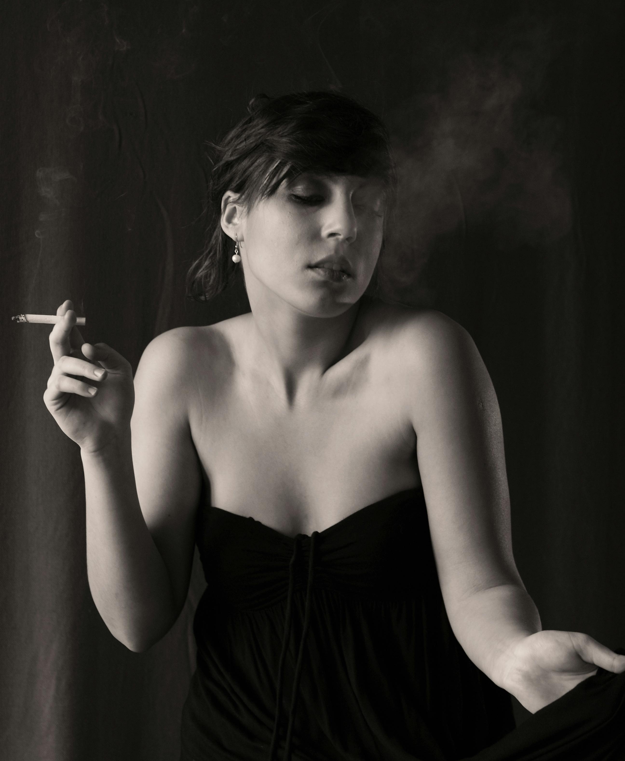 a woman in a black dress smoking a cigarette