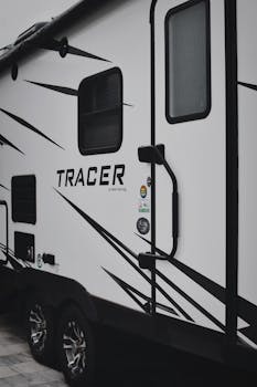 Detailed close-up of the Tracer camper showing door, decals, and wheels for RV enthusiasts.