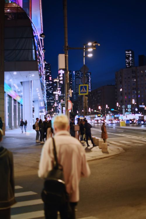 Free Downtown cityscape at night with pedestrians walking under illuminated skyscrapers. Stock Photo