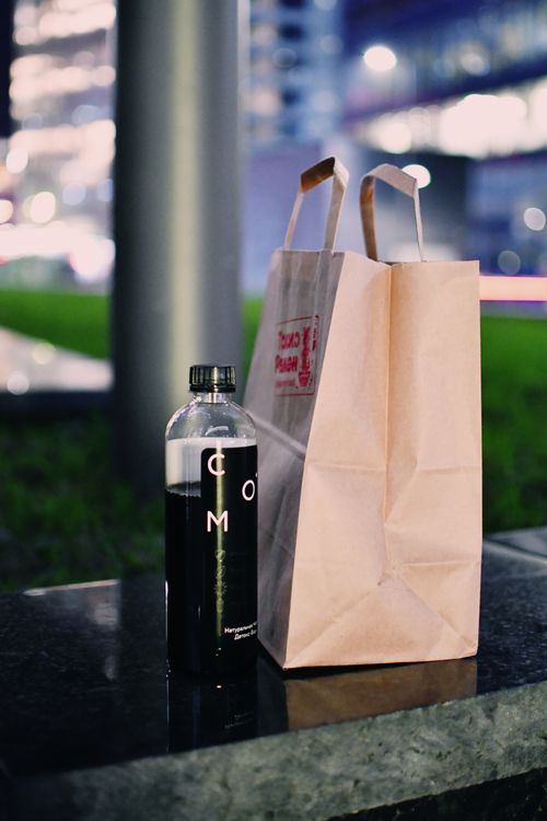 Free A paper bag and bottled drink on an urban bench during twilight. Stock Photo