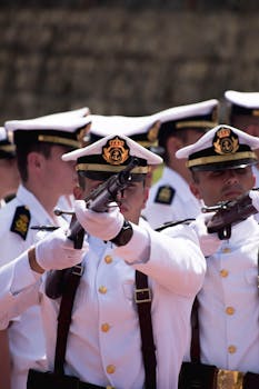 Navy officers in uniform perform a ceremonial drill with rifles, showcasing discipline and precision.