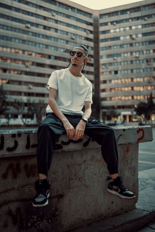 Free Fashionable young man poses in an urban environment with city buildings in the background. Stock Photo