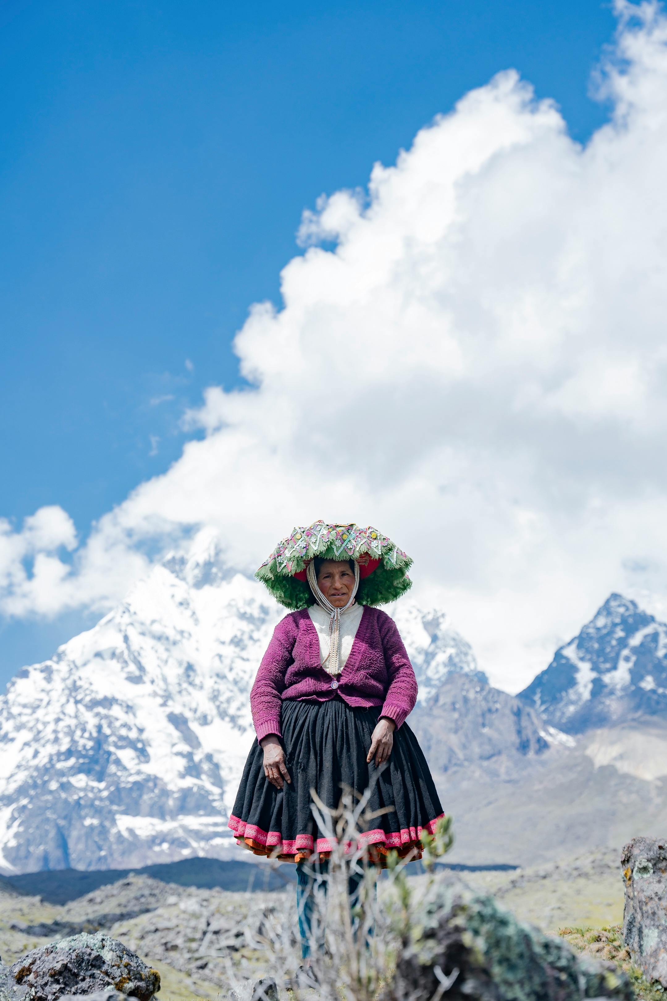 Peruvian woman in traditional attire amidst Andes mountains in Cusco.