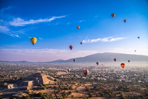 Hotair balloon flying over pyramid in mexico during sunrise