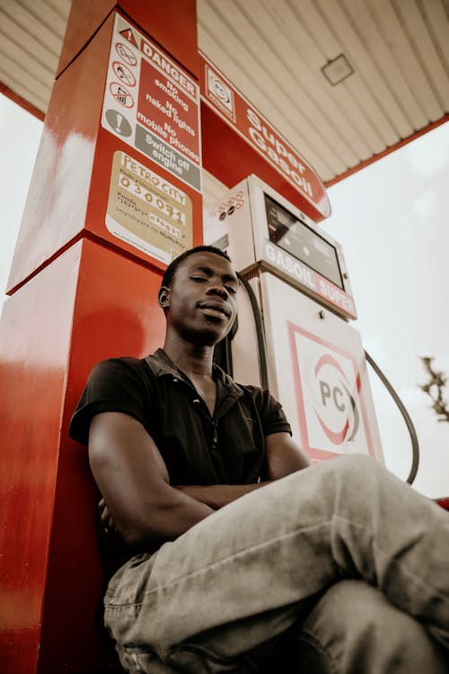 Man Sitting and Posing by Fuel Dispenser