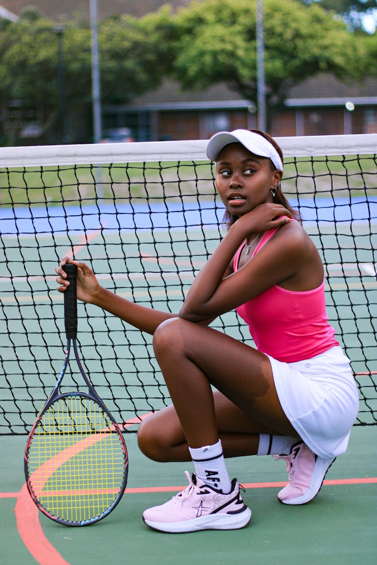 Woman Posing With Tennis Racket By Net On Court