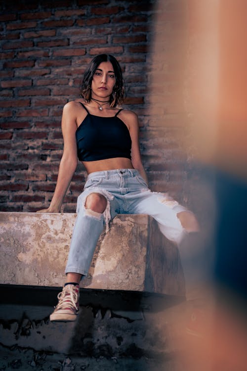 Brunette Woman Sitting in Front of a Brick Wall