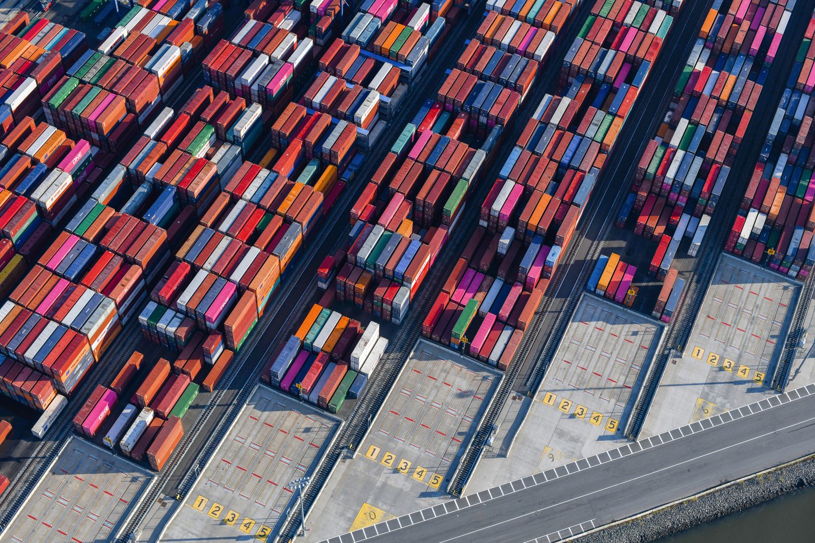 Aerial view of stacked shipping containers in rows at a port terminal
