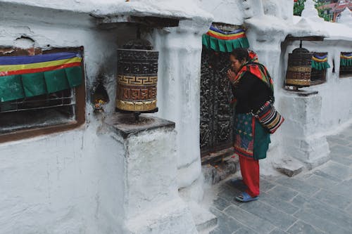 Woman by Buddhist Temple with Prayer Wheels