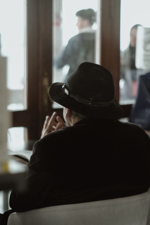 Free A man wearing a hat is relaxing indoors at a café in Istanbul, Turkey, viewed from behind. Stock Photo