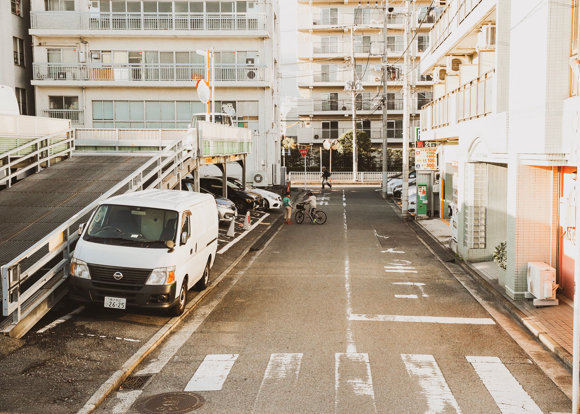 A serene urban street with parked cars, a bicycle, and modern apartments during sunset.