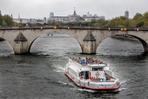 Free Sightseeing boat cruises under an iconic bridge on the Seine River in Paris, France. Stock Photo