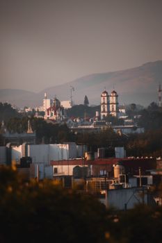 A picturesque view of Puebla de Zaragoza with iconic architecture and distant hills during sunset.