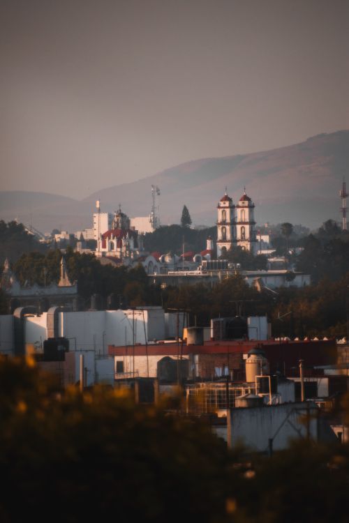 Free A picturesque view of Puebla de Zaragoza with iconic architecture and distant hills during sunset. Stock Photo
