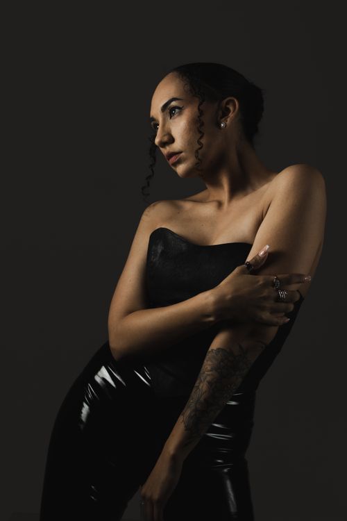 Free An artistic portrait of a woman in sleek black attire posing stylishly, showcasing tattoos gracefully. Stock Photo