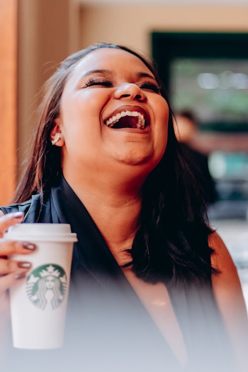 A Laughing Woman Holding a Cup of Coffee