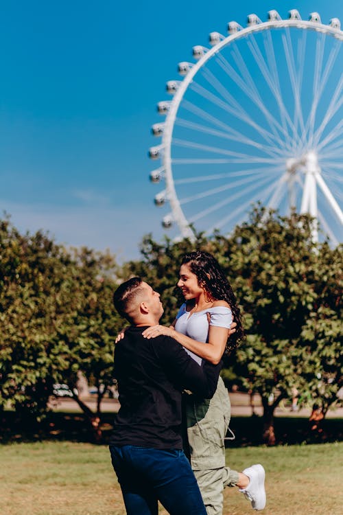 Smiling Couple Hugging in Park with London Eye behind