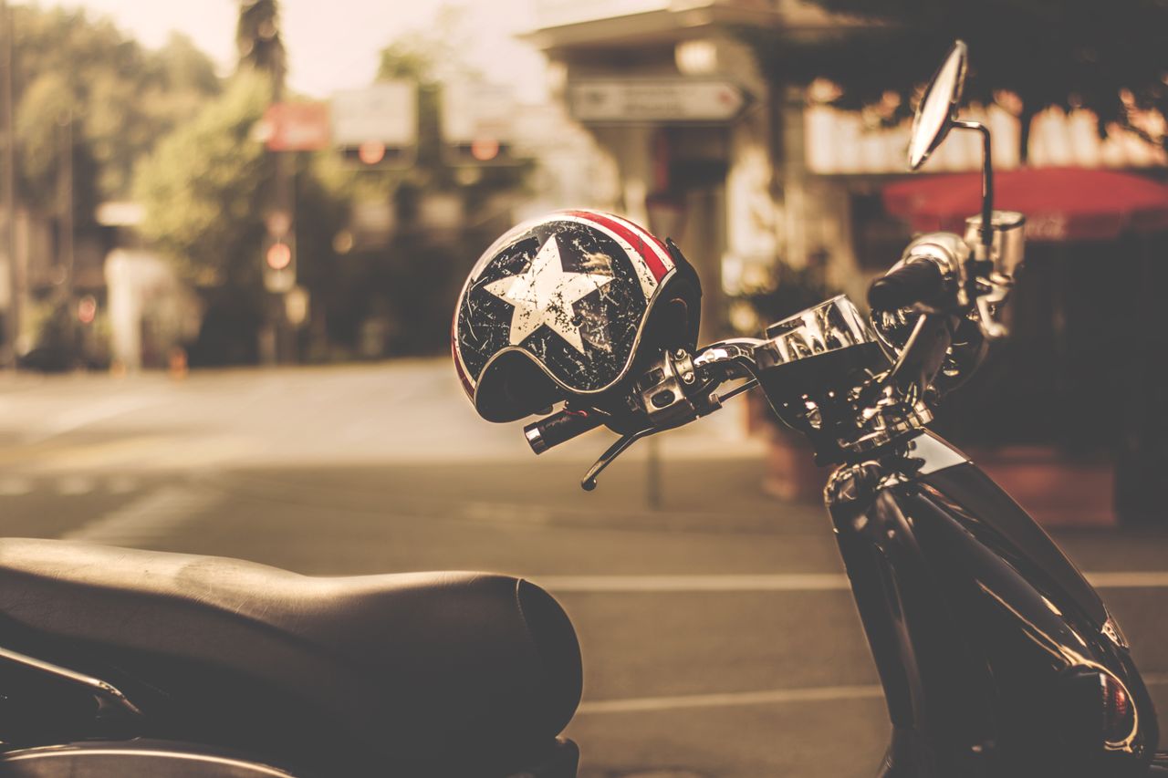 a vintage style helmet rests on a scooter in a sunlit urban environmen