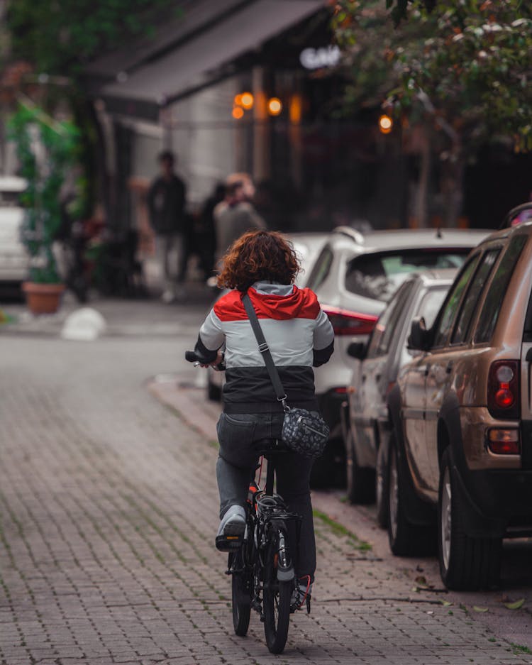 Woman Cycling Near Parked Cars