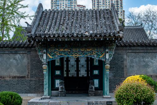 Free A traditional Chinese temple entrance with intricate designs contrasting modern buildings in the background. Stock Photo