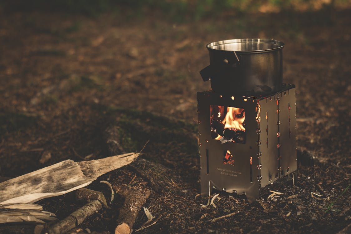 Stainless Steel Pot on Brown Wood Stove Outside during Night Time