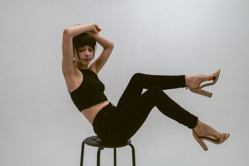 Free A stylish woman in a dynamic pose on a stool, embodying modern fashion and elegance. Stock Photo