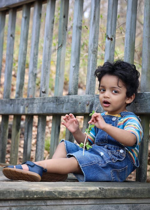 Boy Sitting near Wooden Fence