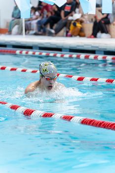 Swimmer in Puno, Peru, wearing a swim cap and goggles, competing in a pool race.