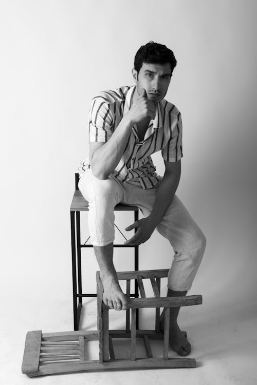Black and White Studio Shot of a Young Man Sitting on a Chair 