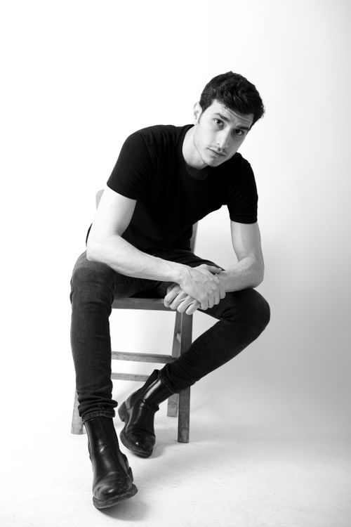 Free Stylish black and white photo of a man posing on a chair in a studio setting. Stock Photo