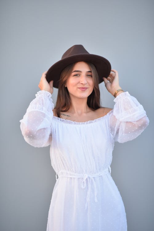 Smiling Woman Posing in Hat and White Dress