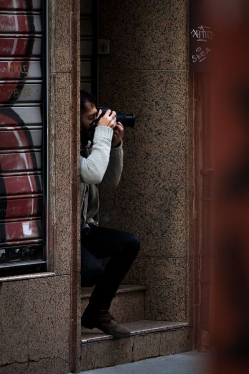 Free A photographer capturing urban scenes while sitting on city steps. Stock Photo