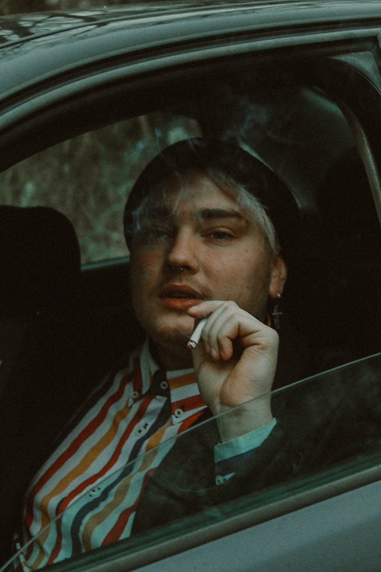 Young Man Sitting In A Car And Smoking A Cigarette 