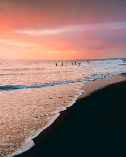 Free Dramatic sunset view over Gokarna beach with silhouettes of people in the water, creating a peaceful and vibrant scene. Stock Photo