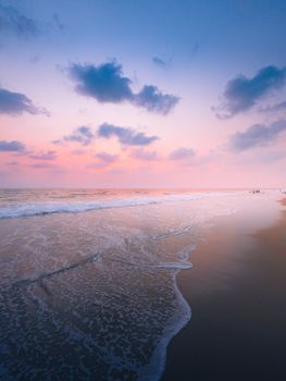 Tranquil view of Gokarna beach with vibrant pink sky and gentle waves at sunset.