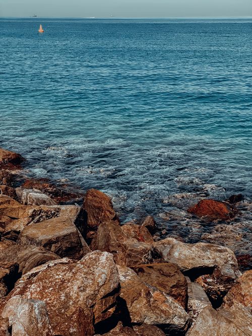 Free Serene coastal scene featuring rocky shoreline and clear blue ocean waters. Stock Photo
