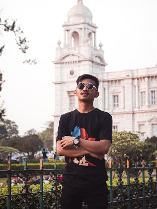 Man in T-shirt Posing in Park with Palace Building behind