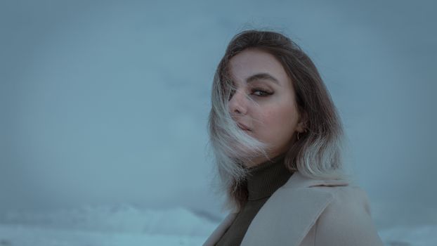 Portrait of a woman in a winter coat amidst a foggy landscape in Karaj, Iran.