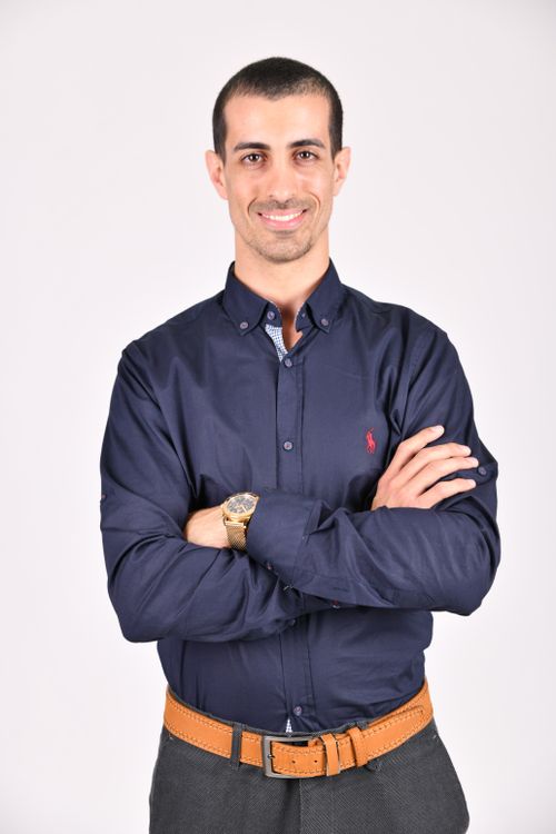 Free Portrait of a confident businessman in a blue shirt with arms crossed, smiling at the camera. Stock Photo