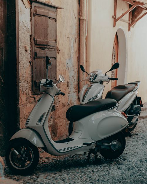 Free Two classic scooters parked in a charming rustic european alleyway. Stock Photo