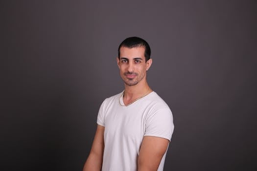 Casual portrait of a young adult man in a studio setting wearing a white shirt.