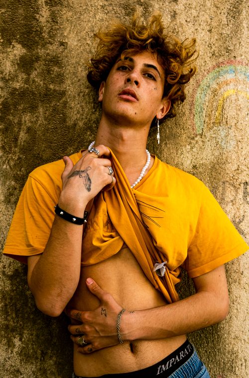 Free Vibrant portrait of a young man in a yellow t-shirt posing against a textured wall. Stock Photo