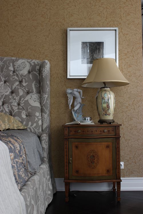 Free Stylish bedroom corner featuring a vintage lamp on a wooden nightstand. Stock Photo