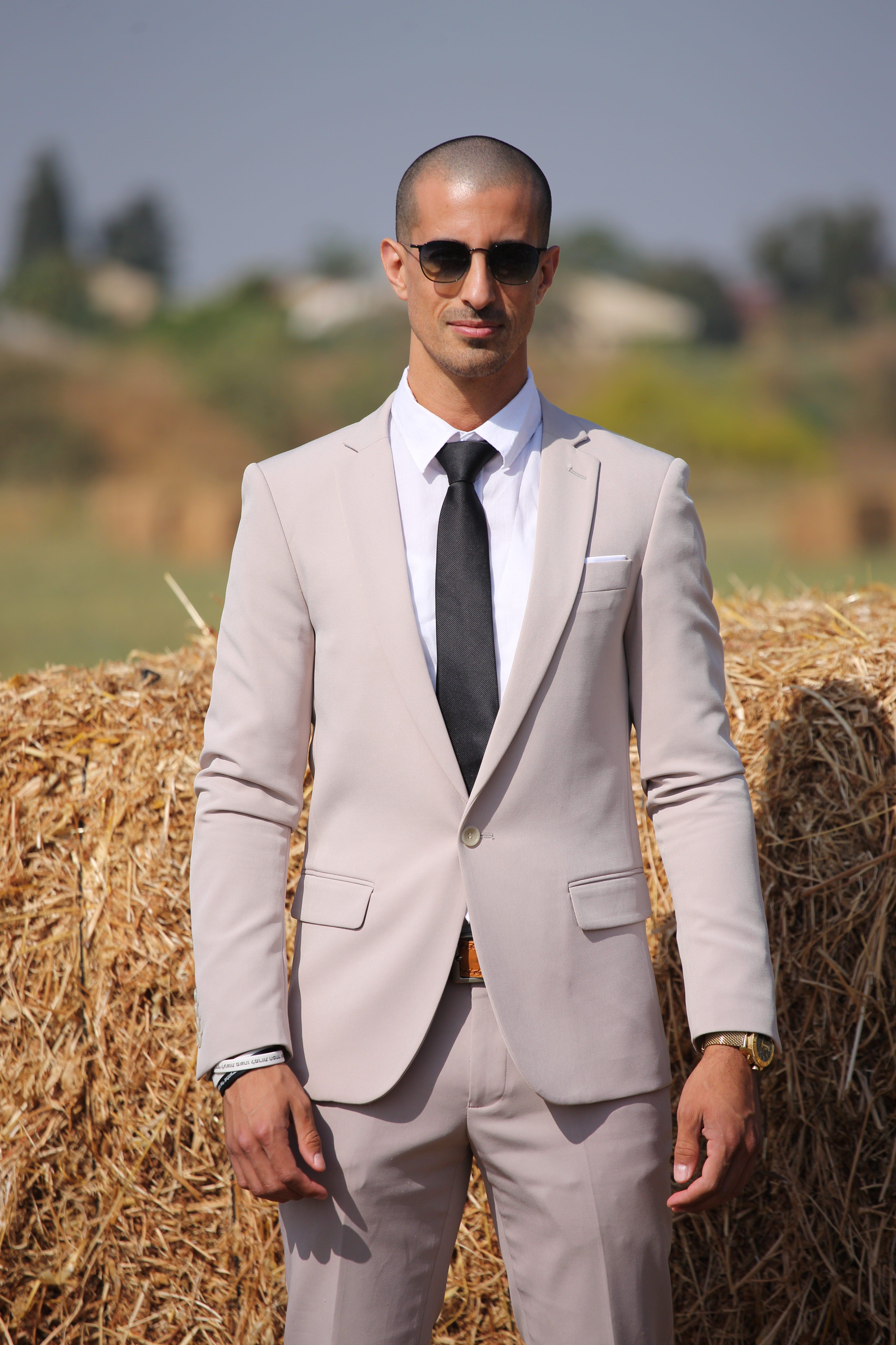 A man in a suit standing in front of hay bales · Free Stock Photo